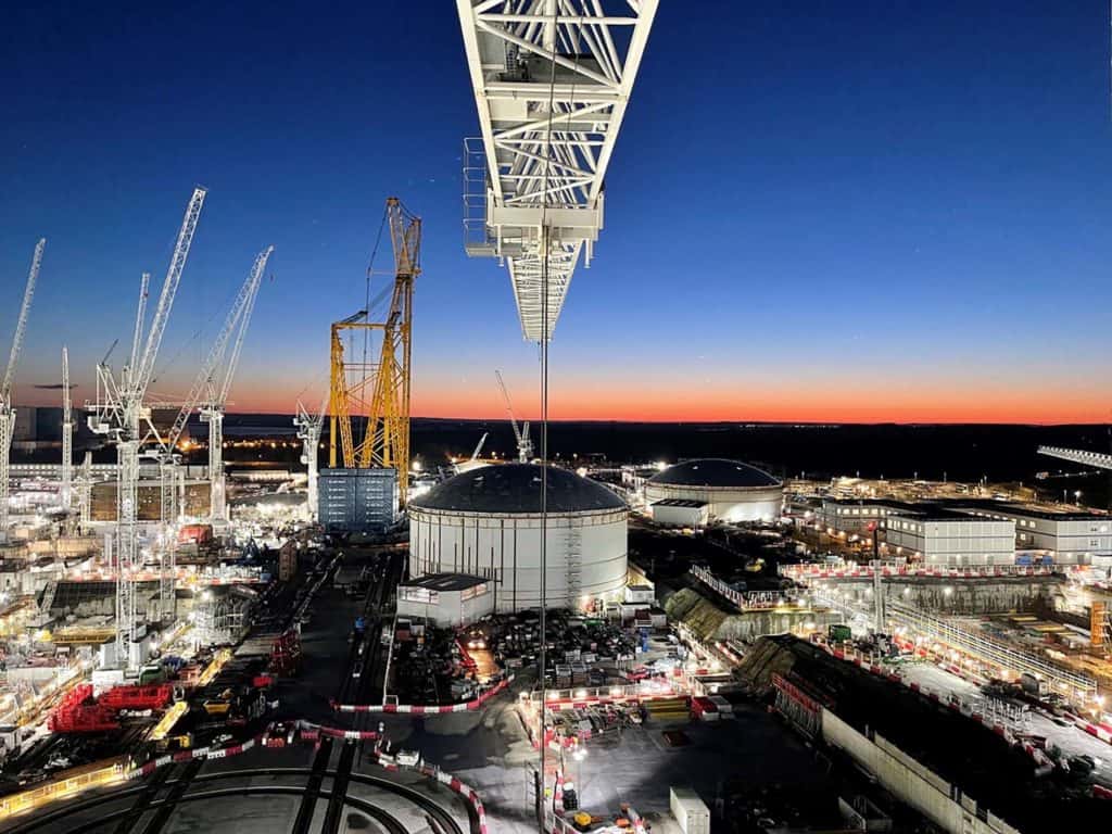 View of construction site on a night time. Large crabes, lifting modular buildings on-site. 